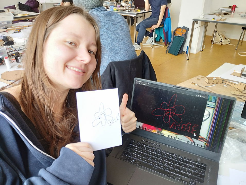 Happy testing person holding a card painted by the machine. The card shows a flower and her name.